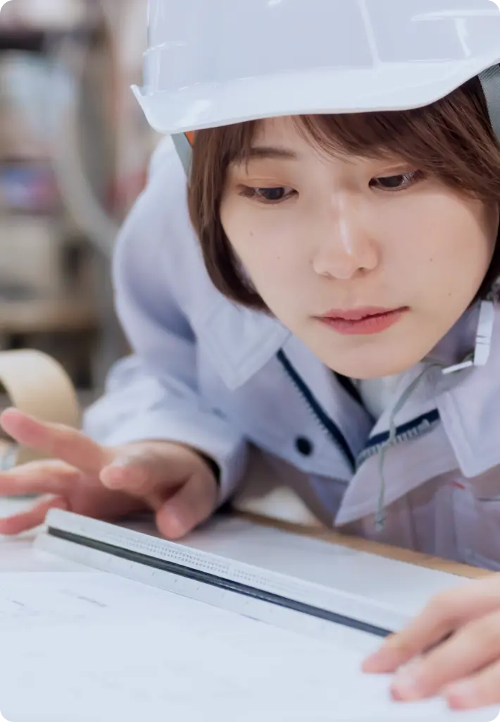 作業着姿で図面を引く女性